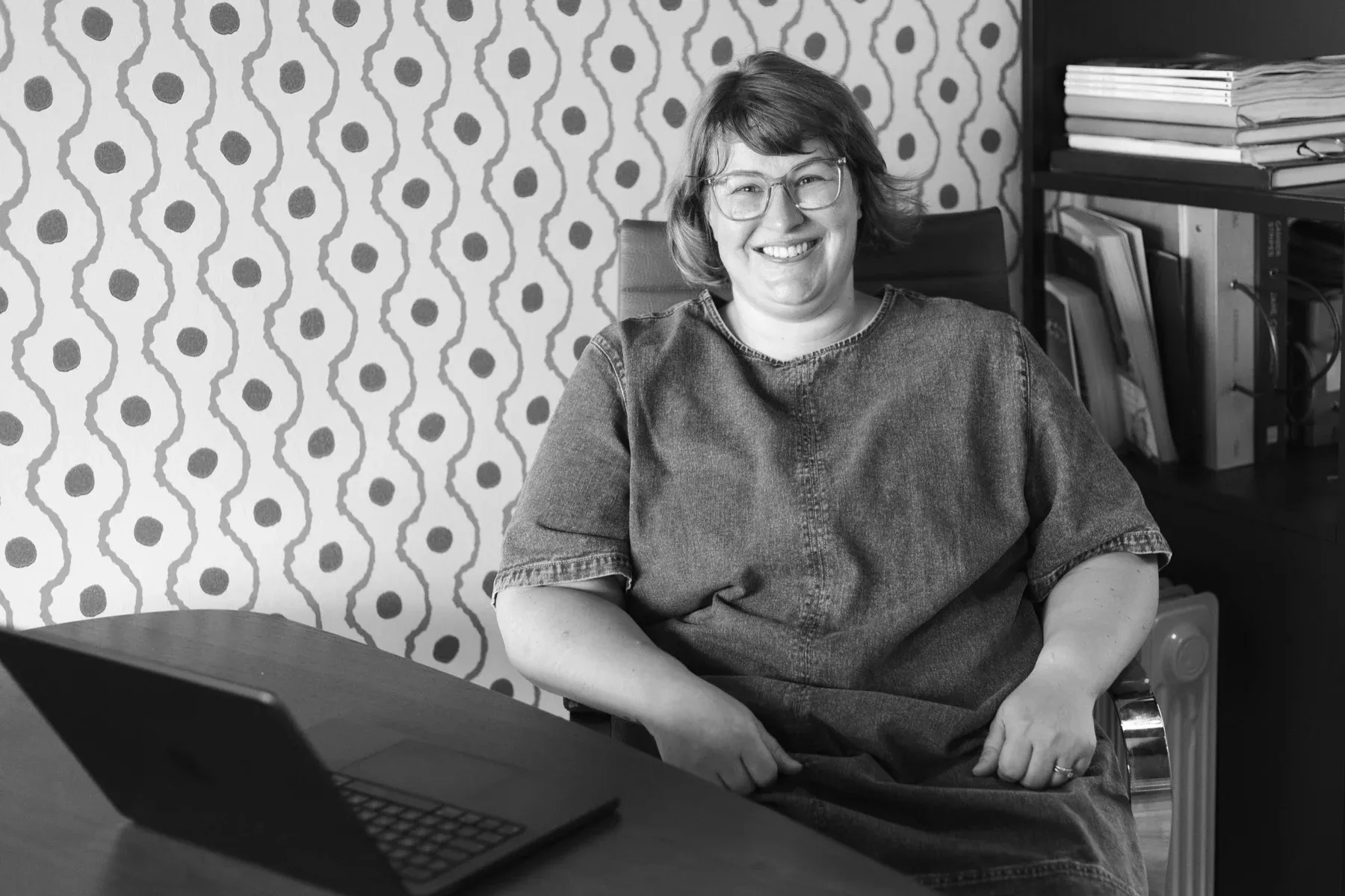 Gemma Hurlstone at her desk with her laptop open, smiling.