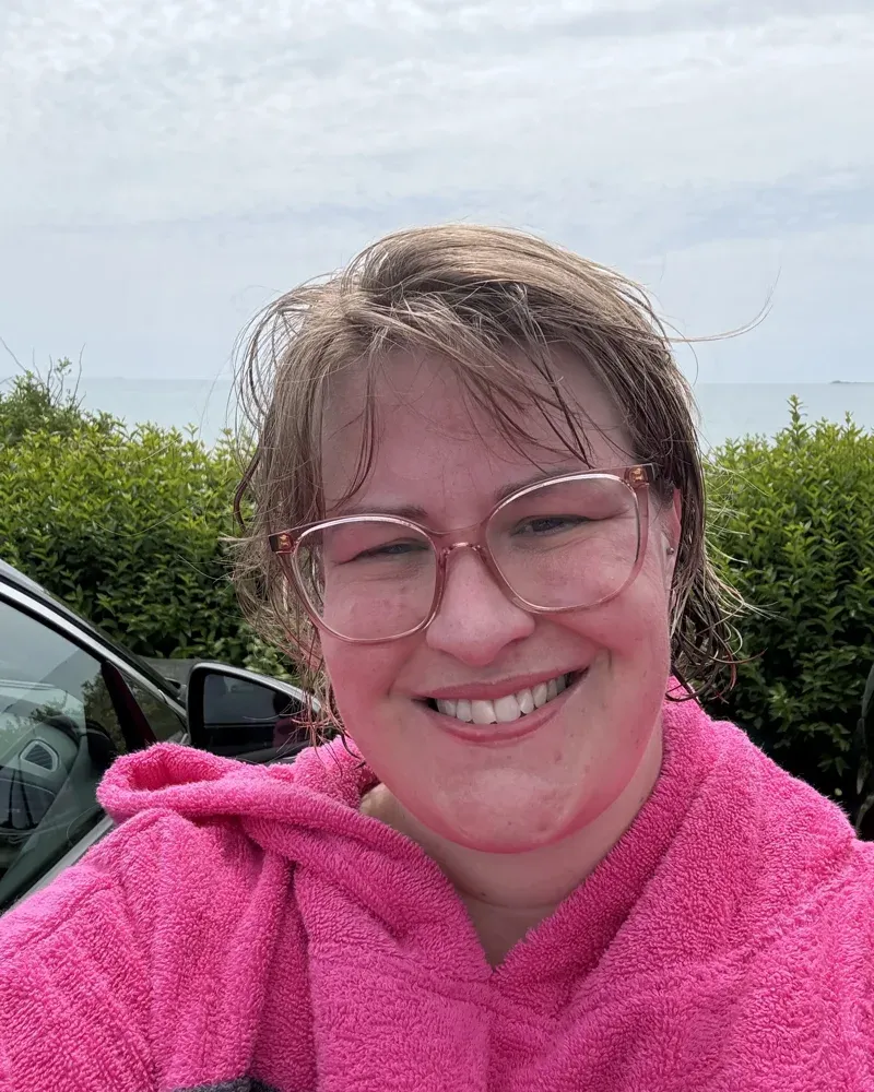 Gemma Hurlstone smiling in a pink towel by the sea in Dorset